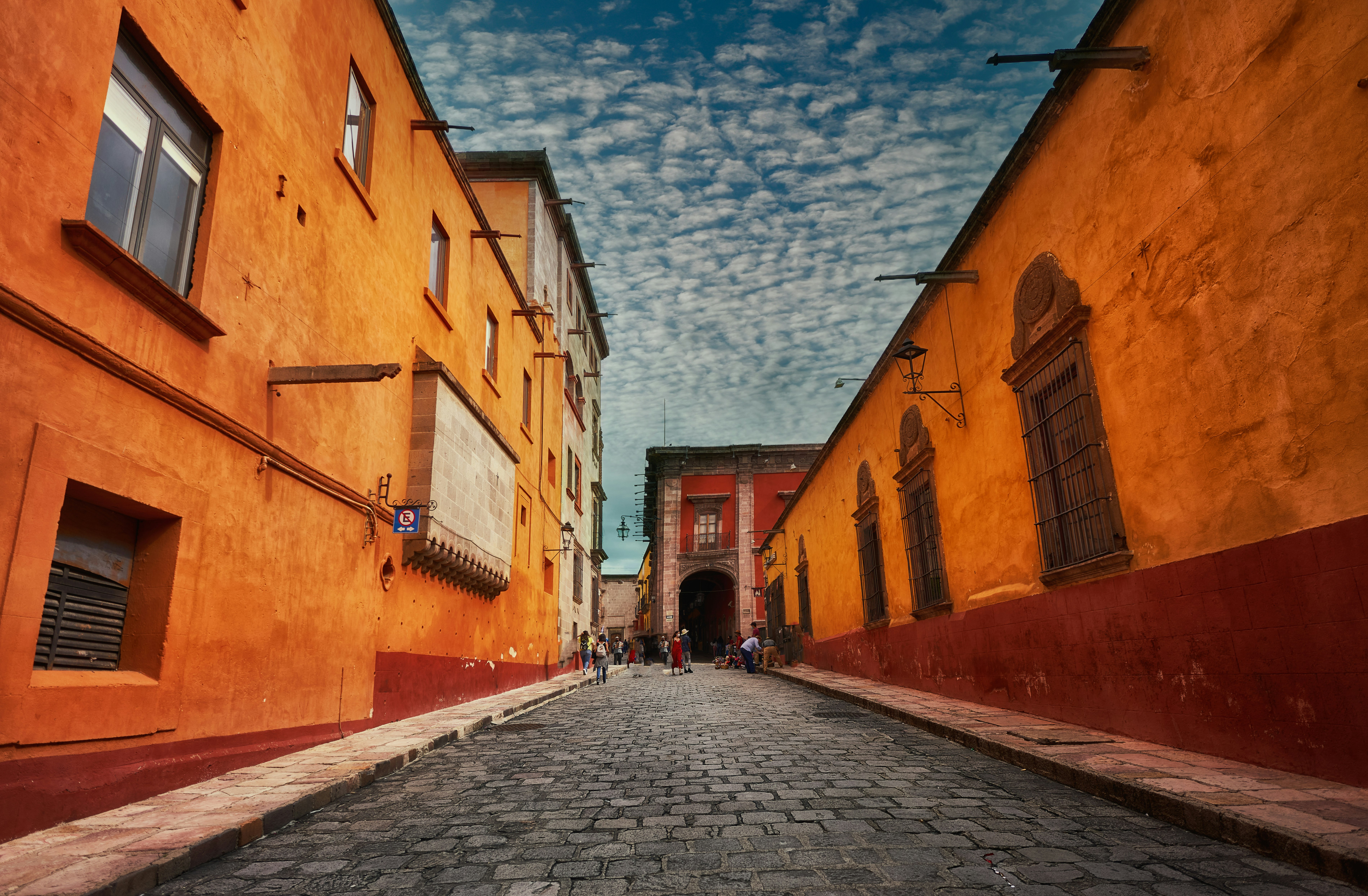 people walking on street between buildings under blue sky during daytime